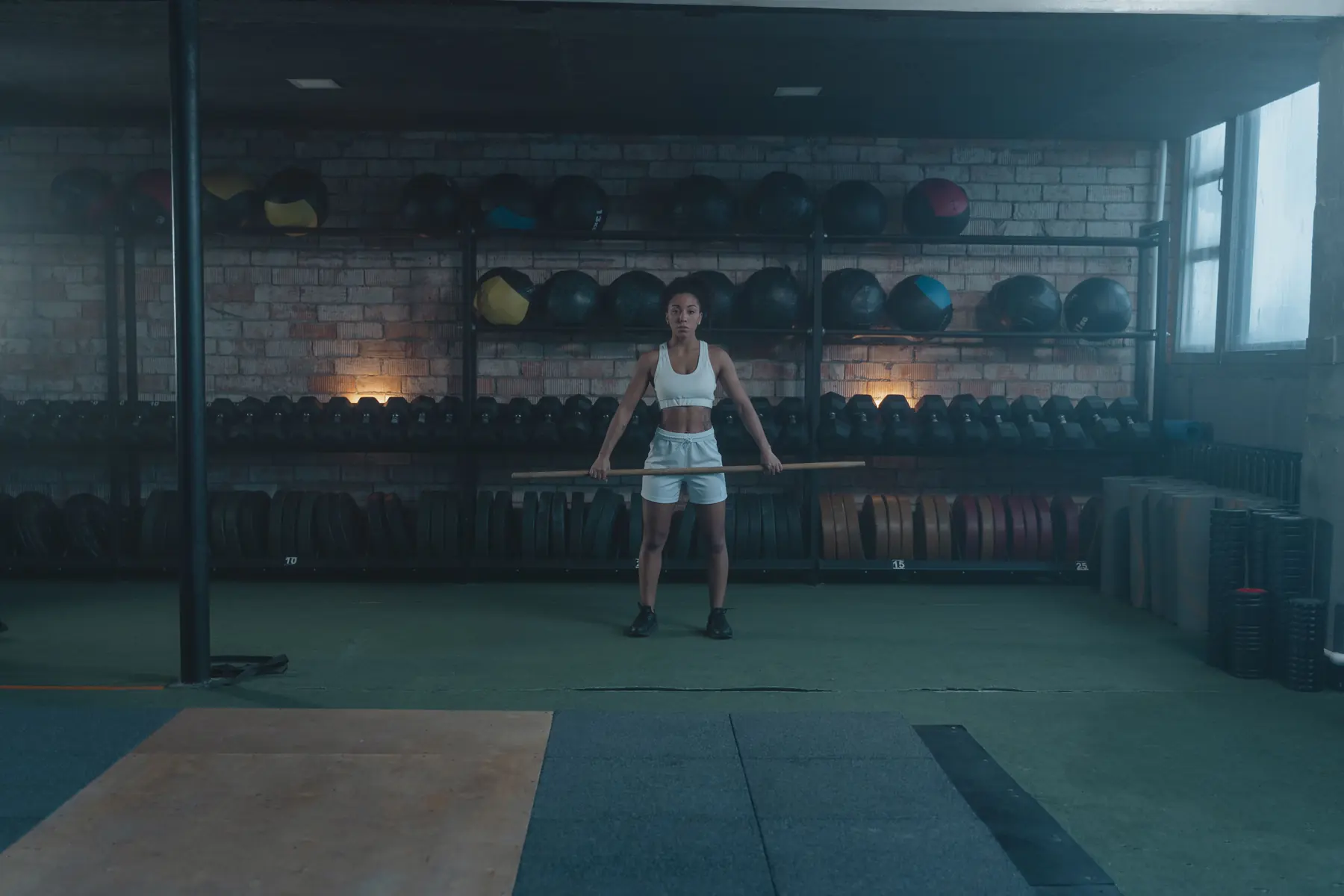 An athlete holds a bar at hip height in front of the medicine-ball wall