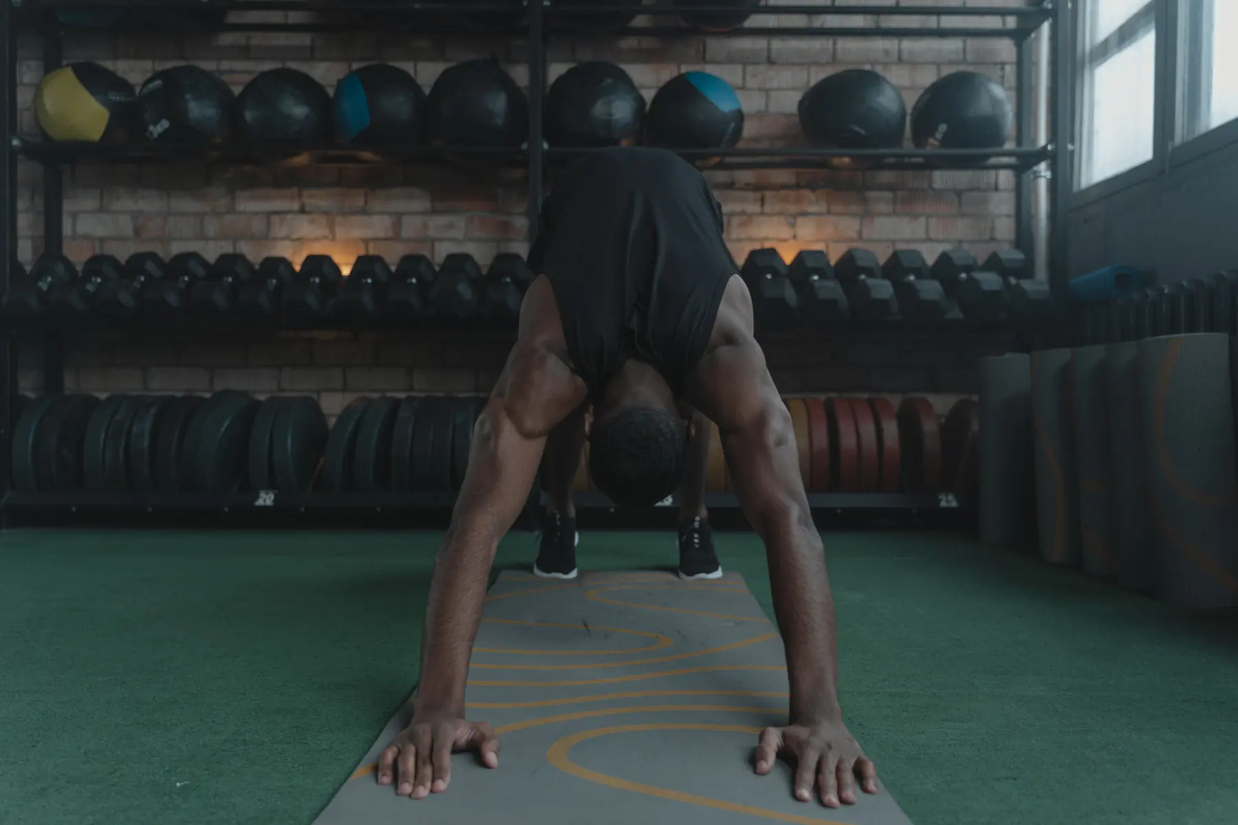 An athlete walks out into an inchworm on a mat in front of the medicine-ball wall