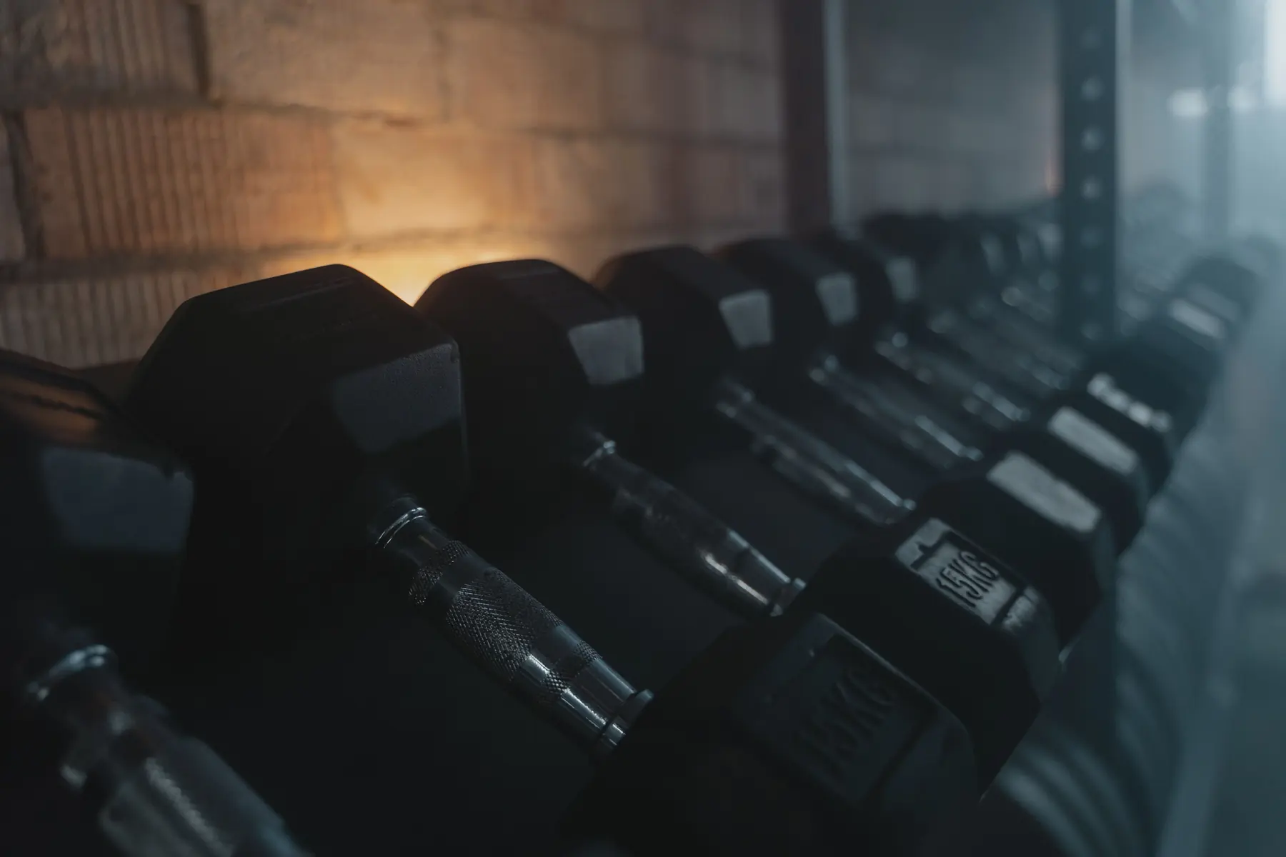 A row of hex dumbbells on the rack in warm light