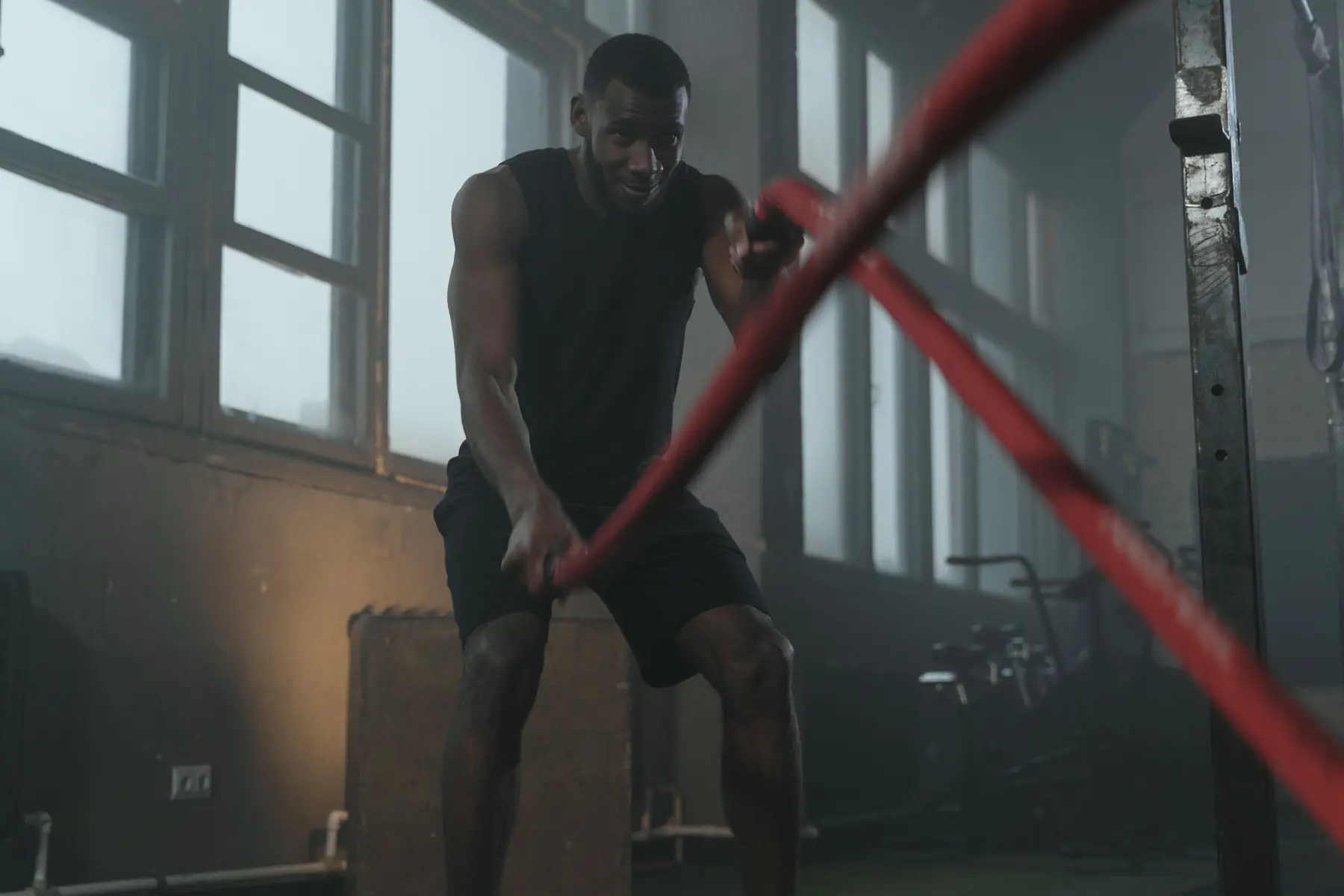 An athlete works heavy battle ropes by the windows