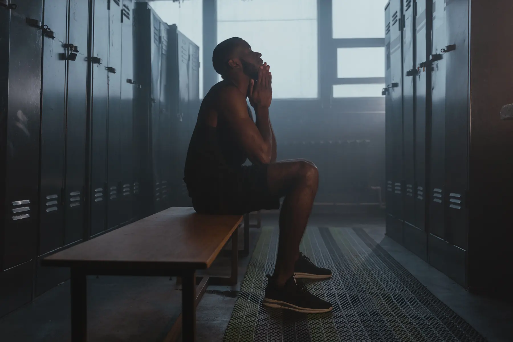 An athlete rests on the bench between the lockers
