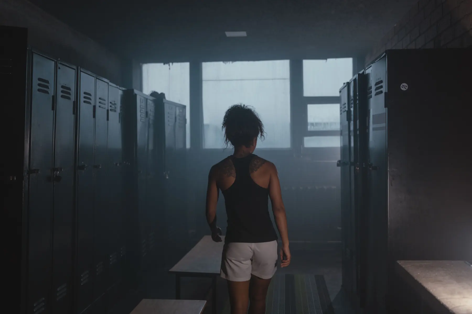 An athlete walks between the lockers towards the window