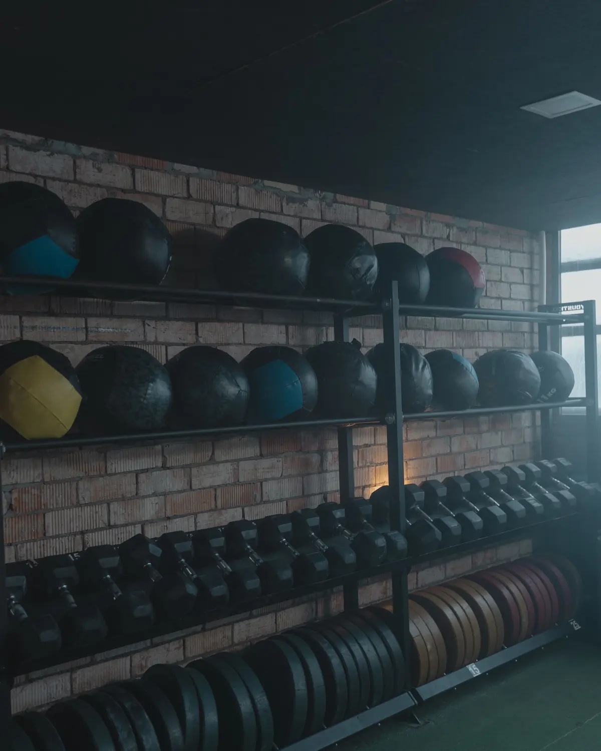 Shelves of medicine balls and dumbbells against the brick wall