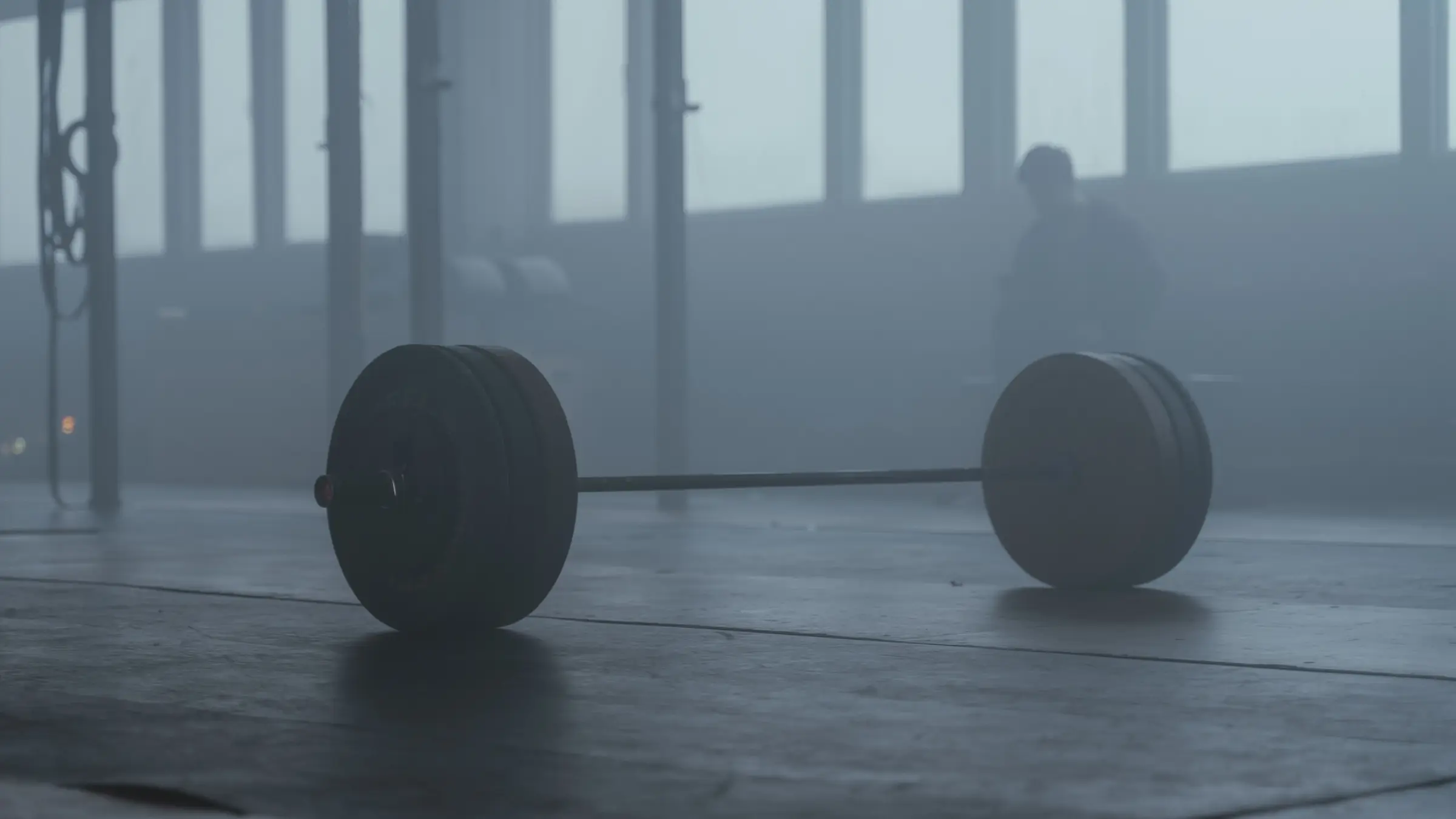 A loaded barbell waiting on the lifting platform in the morning haze of the warehouse floor