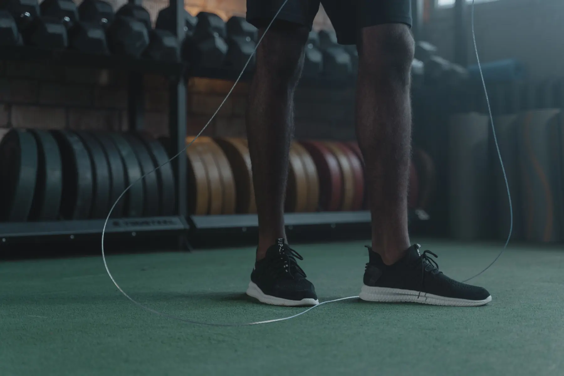 Close view of an athlete's trainers and skipping rope on the turf